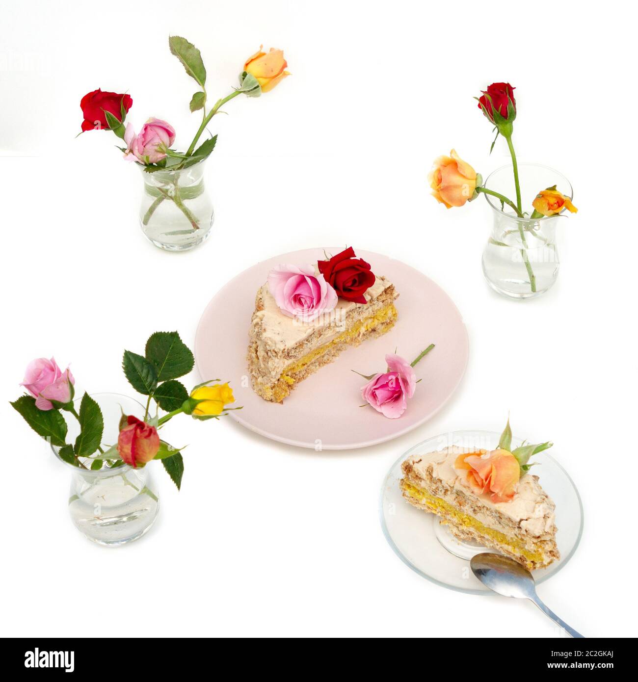 Petit gâteau maison décoré de roses vivantes sur fond blanc. Des roses multicolores sont sur la table dans un armudu en verre. Banque D'Images