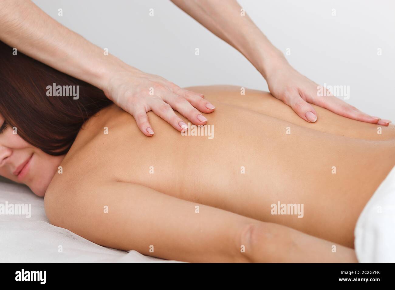 Gros plan d'un massage du dos. Une jeune femme se trouve sur son ventre sur un fond blanc. Mains de masseuse qui se battele la peau du client. Concept pour adver Banque D'Images
