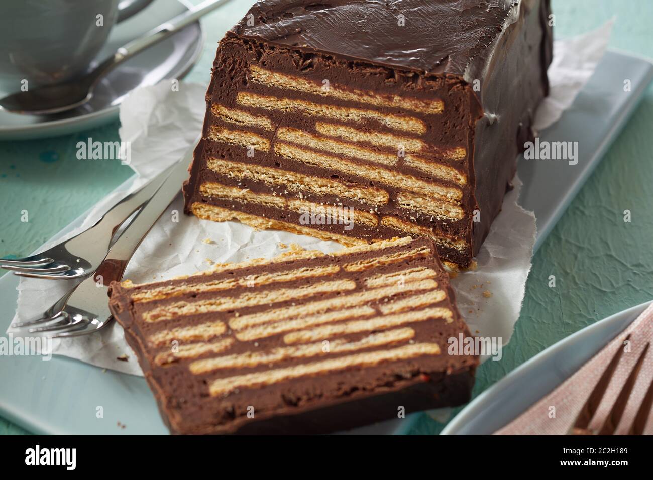 Close-up de maison frais tranchés Kalter Hund biscuit moelleux au chocolat, servi sur le plateau en céramique bleue avec fourches Banque D'Images