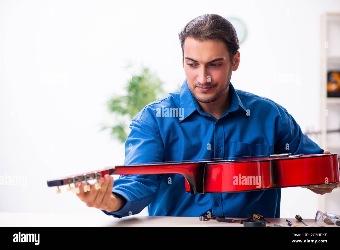 Jeune homme réparateur de la guitare Banque D'Images