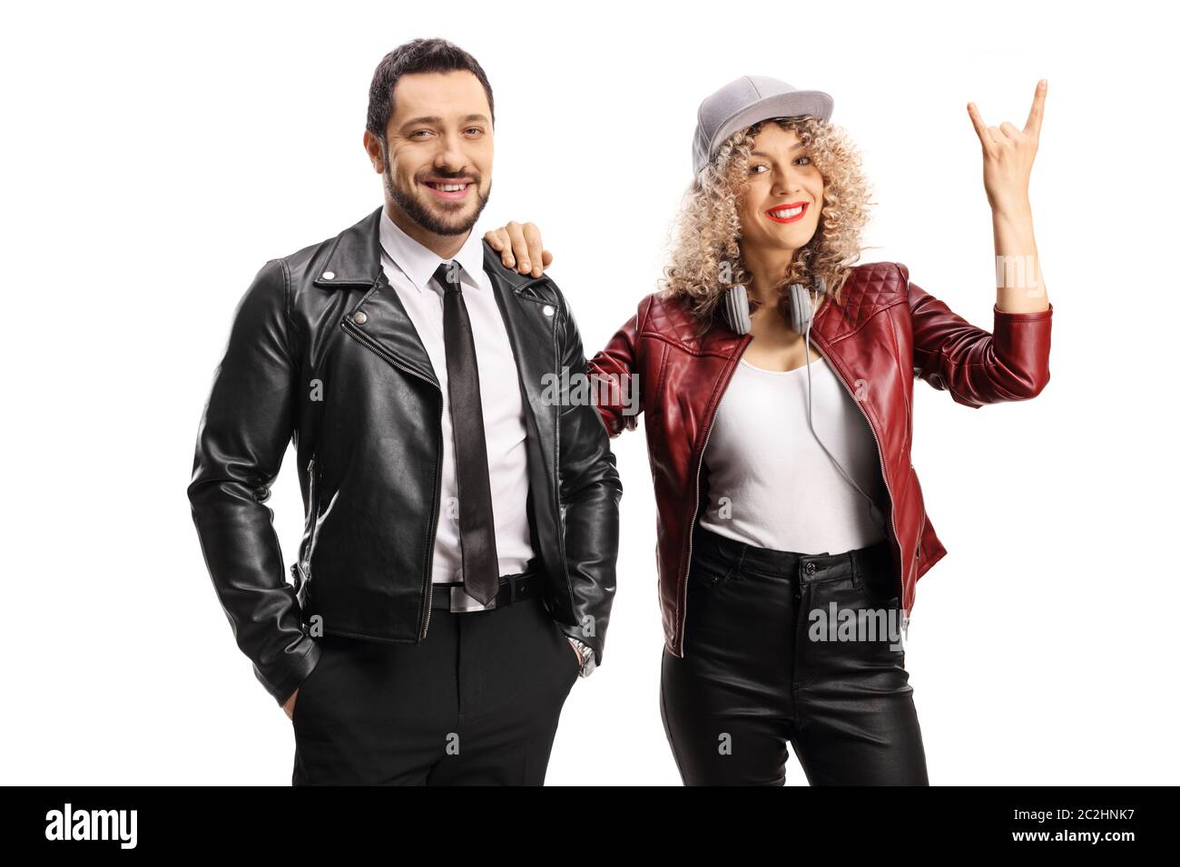 Jeune femme qui fait le geste d'un panneau de rock and roll et qui se tient debout avec un gars dans une veste en cuir isolée sur fond blanc Banque D'Images