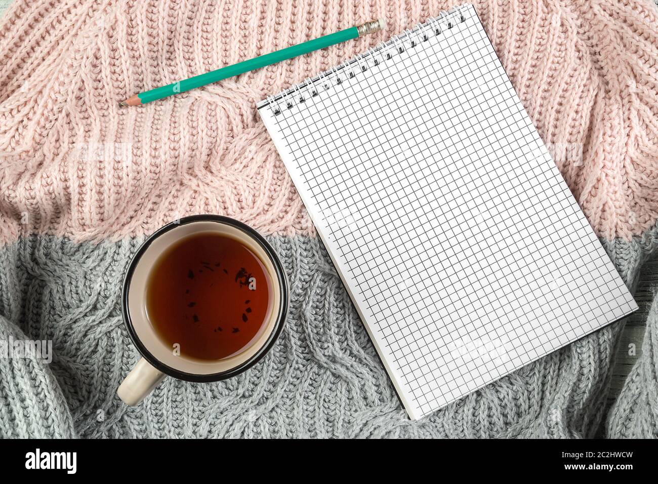 Feuilles d'automne jaunes, une tasse de thé et un carnet sur un pull texturé avec espace vide pour le texte. Vue du haut. plat l Banque D'Images