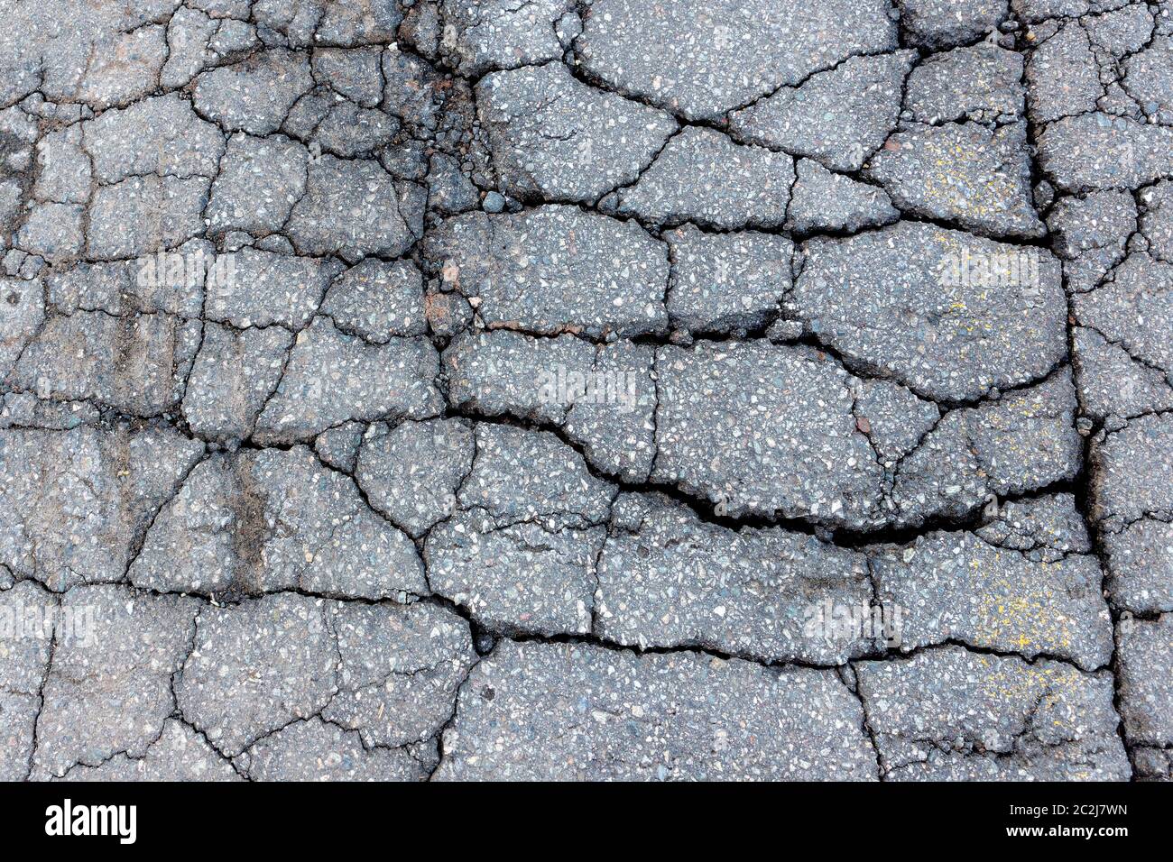 Asphalte fissuré. Route composée d'asphalte sévèrement fissuré. Vue en gros plan vers le bas. Banque D'Images