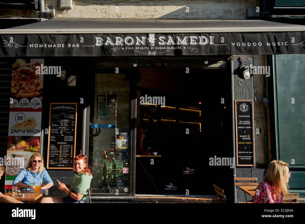 Quatre femmes, une a redhead trois blondes s'assoient hors Baron Samedi bar et restaurant annonçant les spiritueux fins, blondes bon marché ville de Bordeaux France Banque D'Images