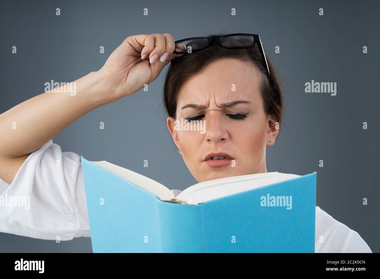 Jeune femme avec des lunettes d'essayer de lire Livre Banque D'Images