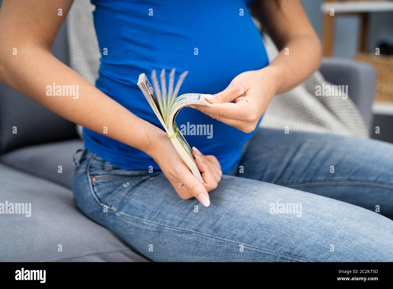 Femme enceinte comptant US Dollar bills à la maison Banque D'Images