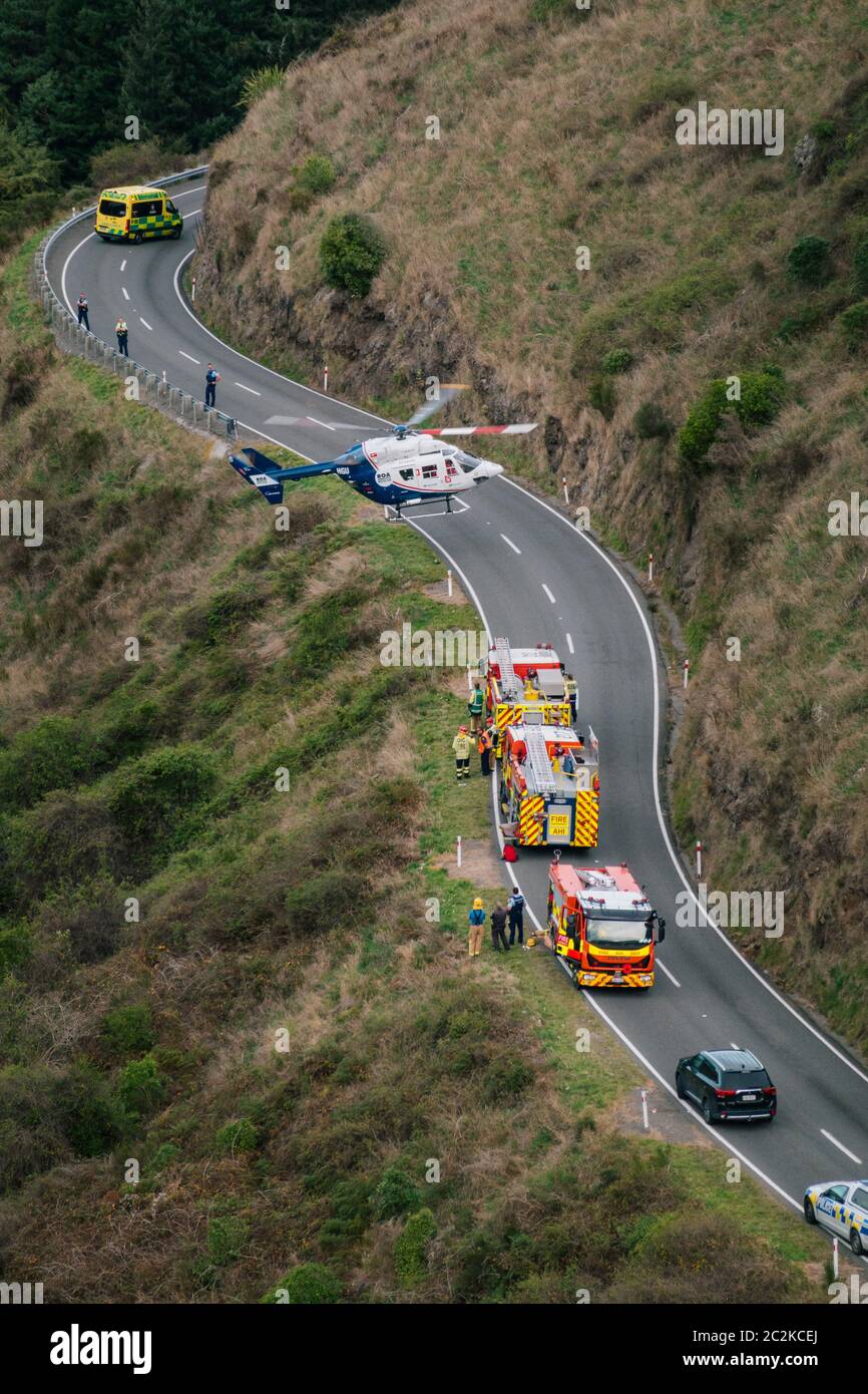 Un hélicoptère de sauvetage MB BK117 / H145 déchaîne d'une route sur le côté d'une montagne à côté des véhicules de service d'urgence Banque D'Images Un hélicoptère de sauvetage MB BK117 / H145 déchaîne d'une route sur le côté d'une montagne à côté des véhicules de service d'urgence Banque D'Images