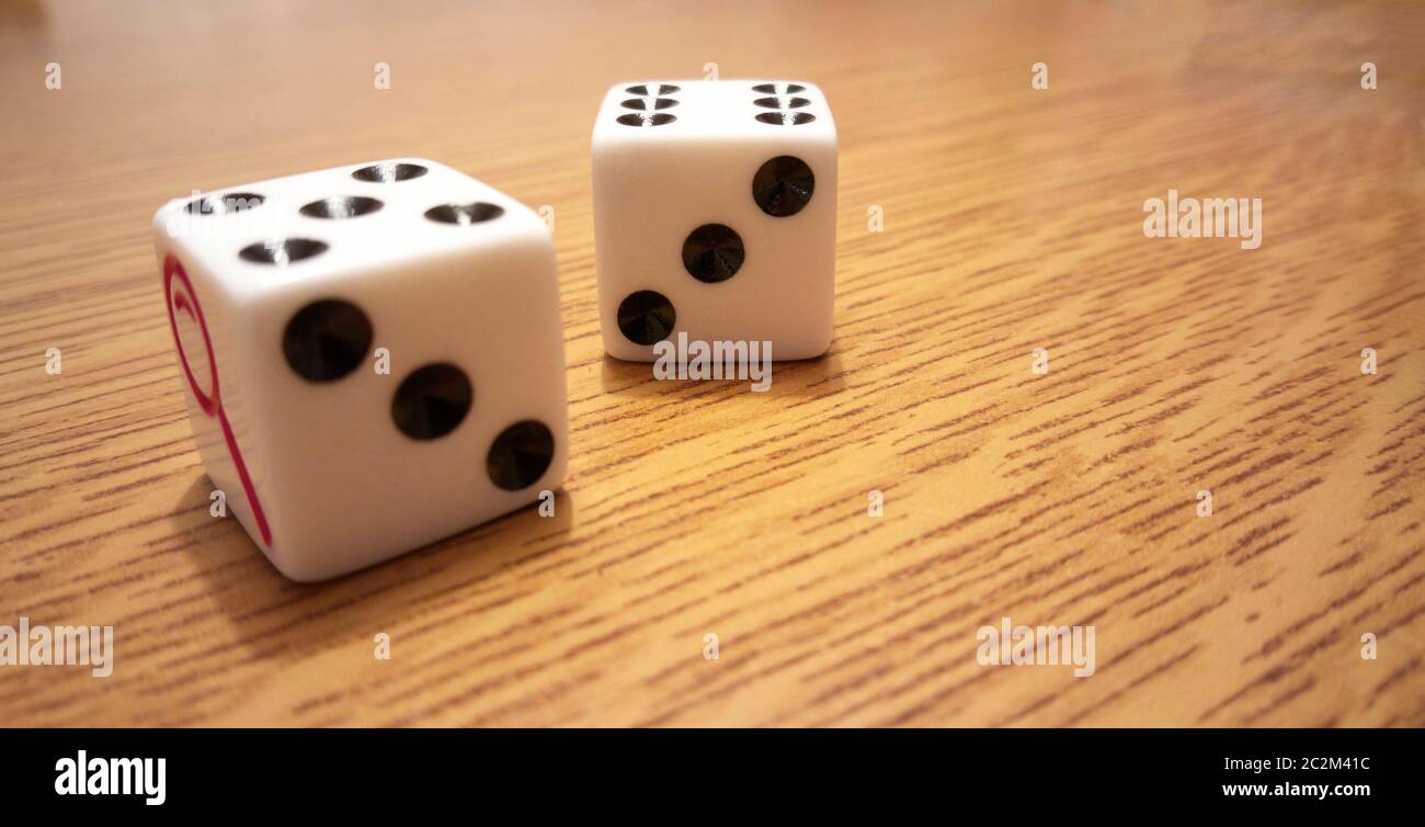 Deux dés blancs avec des numéros noirs sur une table en bois clair. Banque D'Images