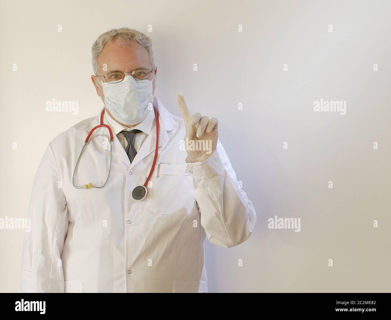 Tablier de médecin masculin avec masque médical de protection et gants disant NON avec le geste de doigt à la clinique ou à l'hôpital protection de la santé pour Corona virus COVID Banque D'Images Tablier de médecin masculin avec masque médical de protection et gants disant NON avec le geste de doigt à la clinique ou à l'hôpital protection de la santé pour Corona virus COVID Banque D'Images