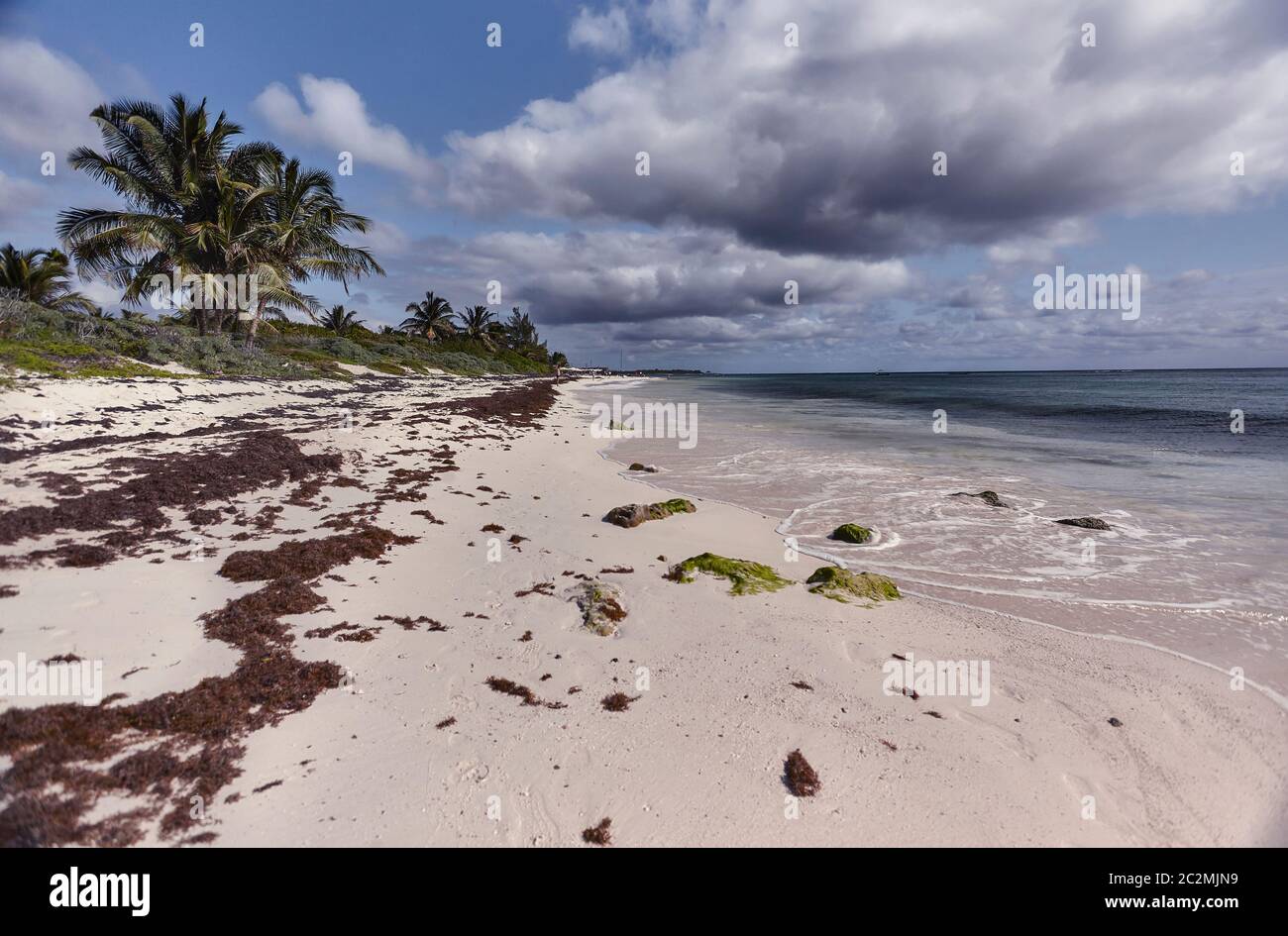 Vue panoramique sur la plage de Xpu-Ha au Mexique pendant une journée ensoleillée avec des nuages épars qui couvrent parfois la lumière. Banque D'Images