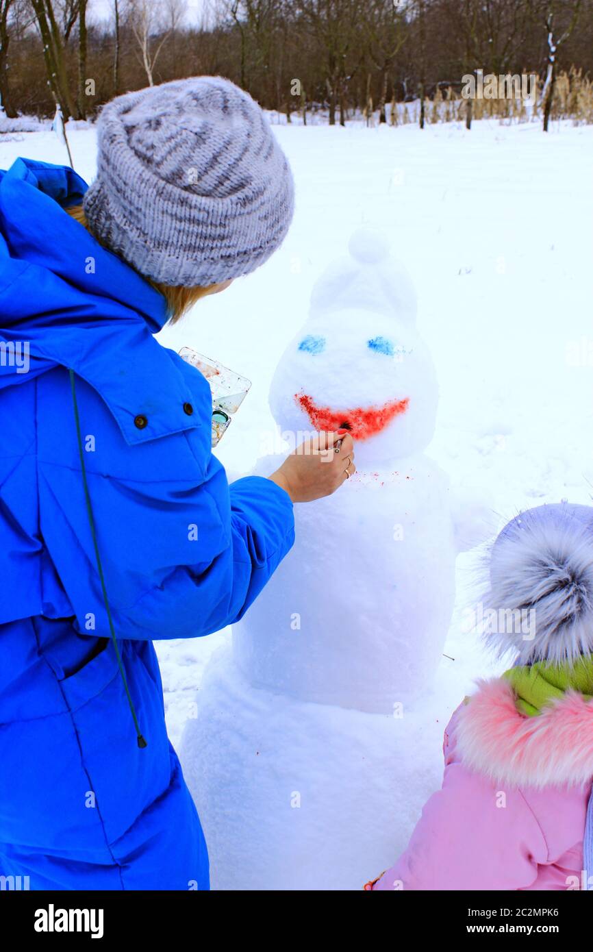 Mère et fille peignent bonhomme de neige. Bonhomme de neige gros plan. Vacances d'hiver. Programme de la nouvelle année Banque D'Images