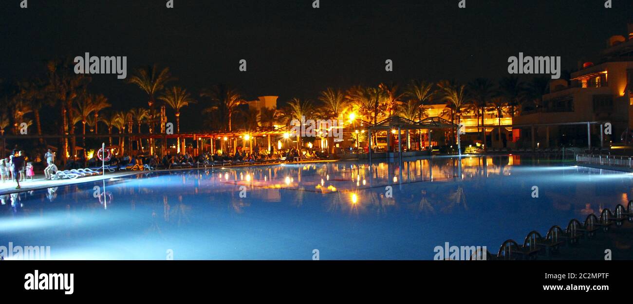 Piscine et hôtel en soirée pendant les vacances. Les gens se détendent le soir près de la piscine Banque D'Images