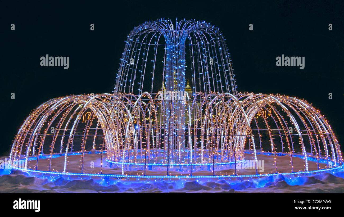 Belle fontaine de guirlande de vacances colorées scintillant et clignotant dans le parc de la ville en hiver Banque D'Images