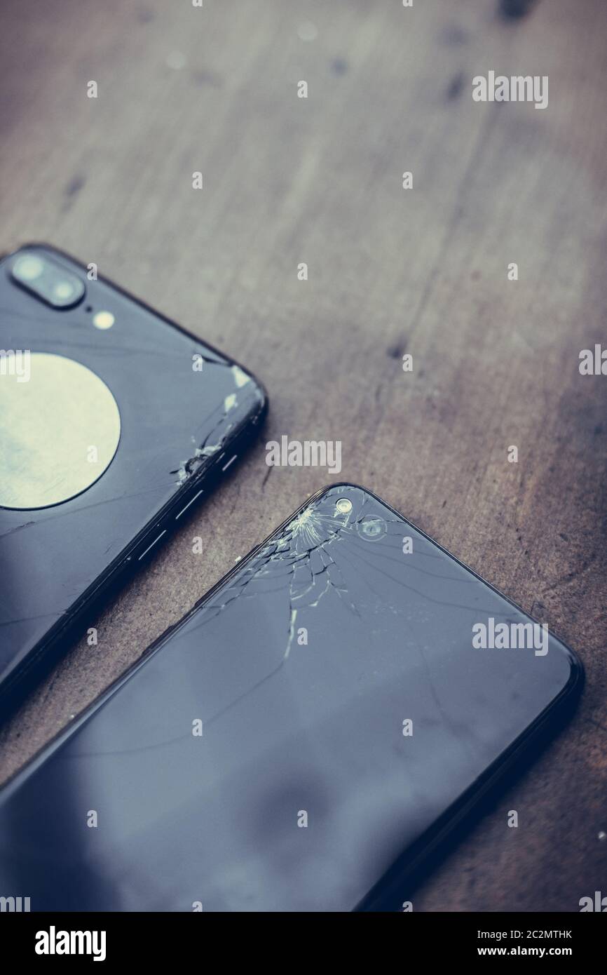 Rapprochée sur certains téléphones mobiles avec écrans cassés sur une table en bois. Banque D'Images