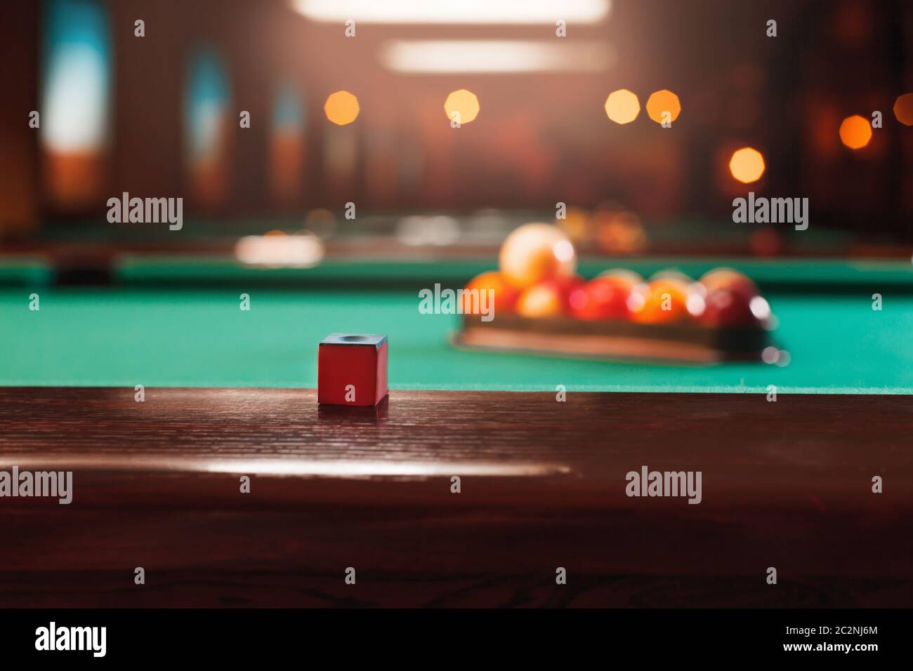 Craie sur le bord en bois de la table de billard. Boules dans un triangle de piscine sur l'arrière-plan. Banque D'Images