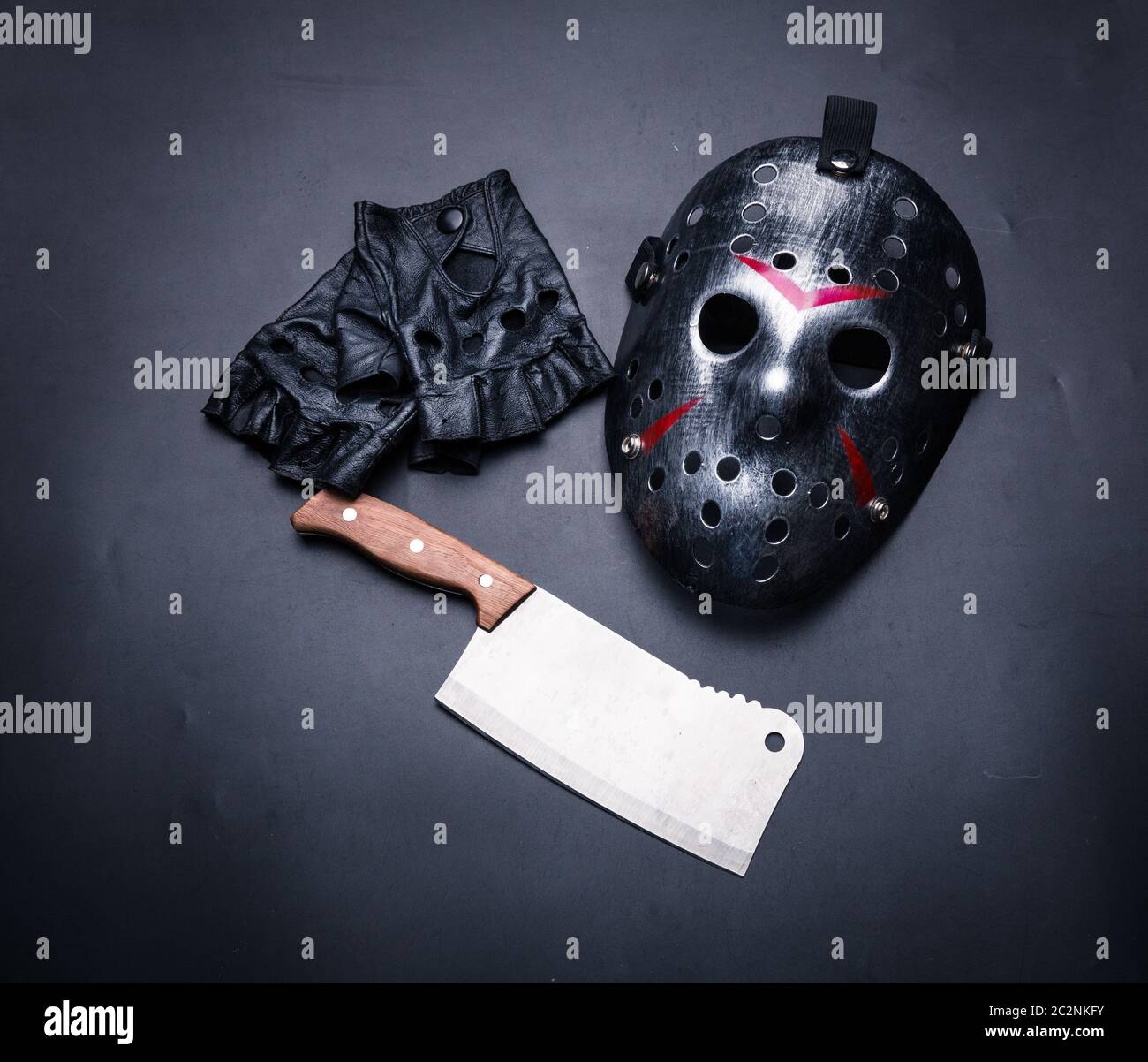 Psycho fou instruments homme isolé sur fond noir. Masque de hockey avec bandes sanglante, sans doigts Gants de cuir et de viande cleaver. Tueur en série Banque D'Images