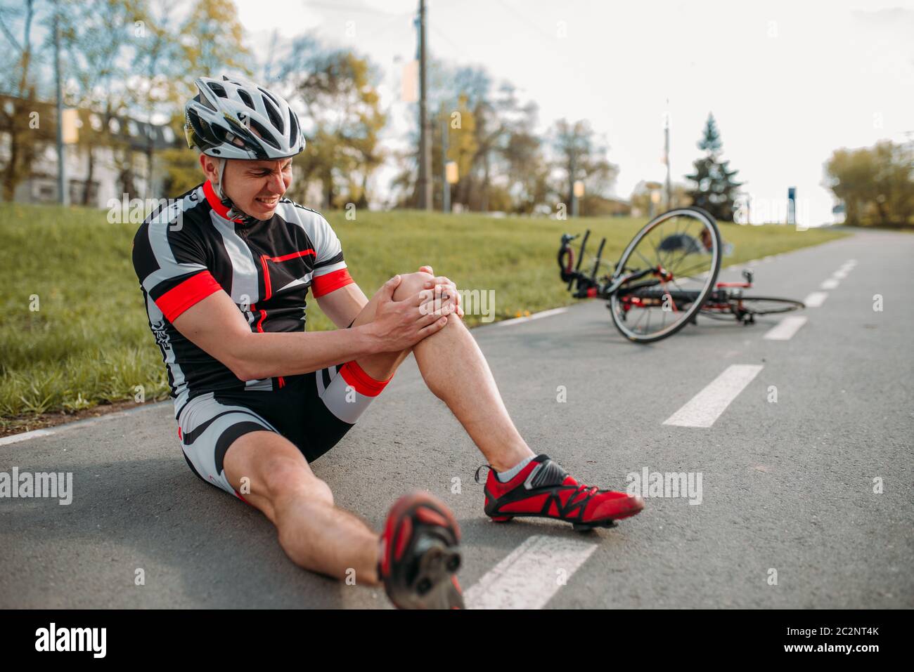 Homme bycyclist est tombé de vélo et a frappé son genou, cyclisme sur piste cyclable. Randonnées à vélo sportif Banque D'Images