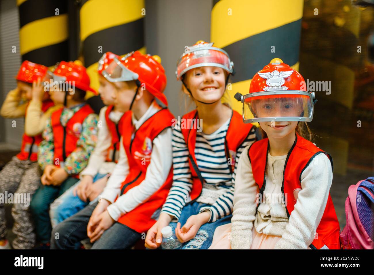 Enfants en casques et uniforme jouant pompier, salle de jeux intérieure. Enfants lerning pompier profession. Garçons et filles jouent les sauveteurs, les petits héros Banque D'Images