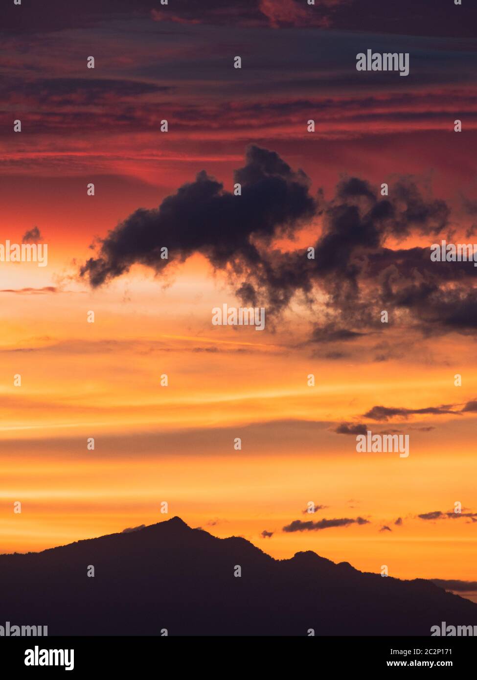 Ciel doré et rose, avec une silhouette de nuage sur une montagne. Banque D'Images