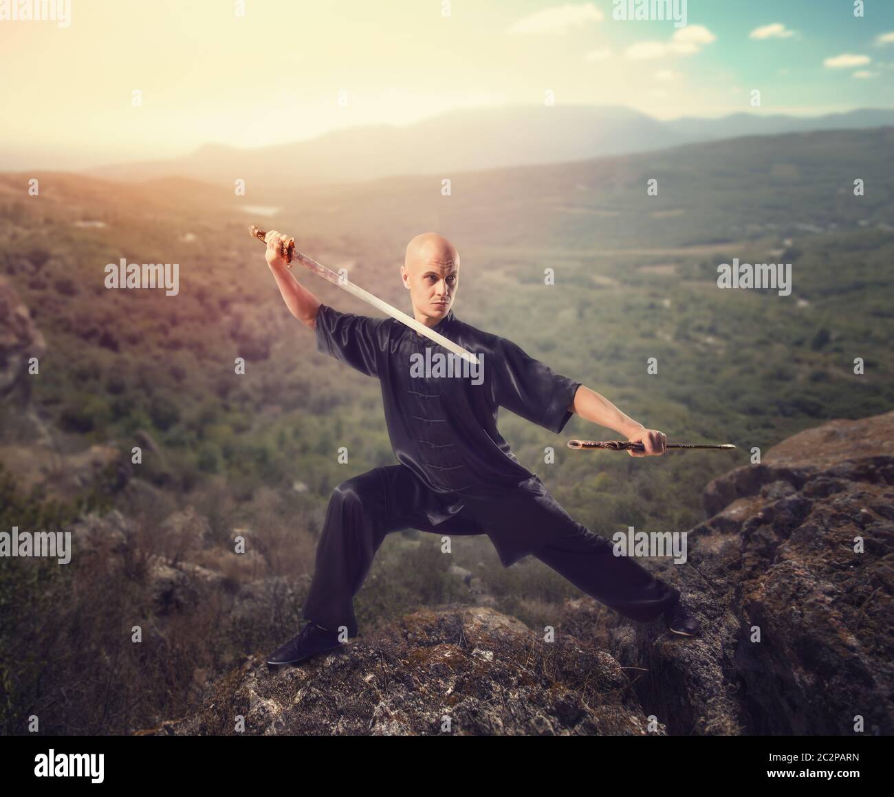 Maître de Wushu à l'épée, la méditation sur le sommet de la montagne, les arts martiaux en homme tissu noir pose avec lame Banque D'Images
