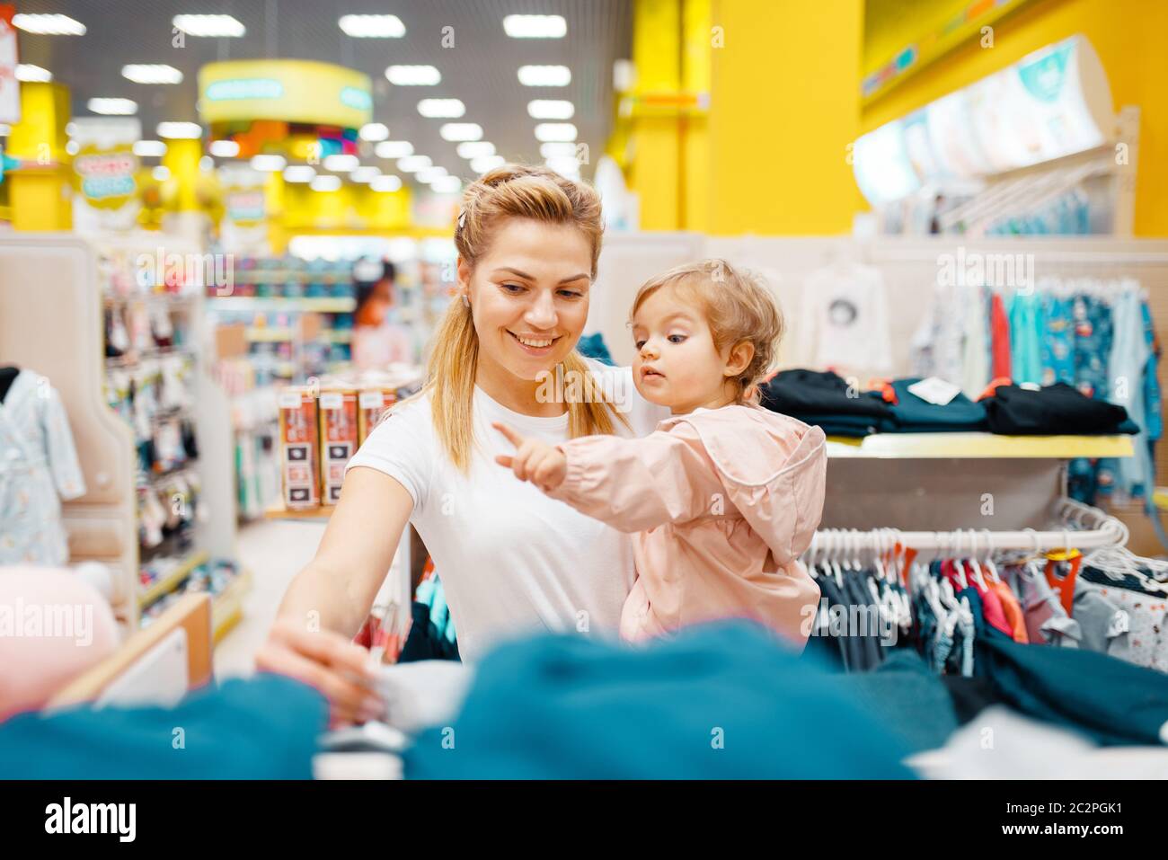 M re avec sa petite fille qui choisit des v tements dans le
