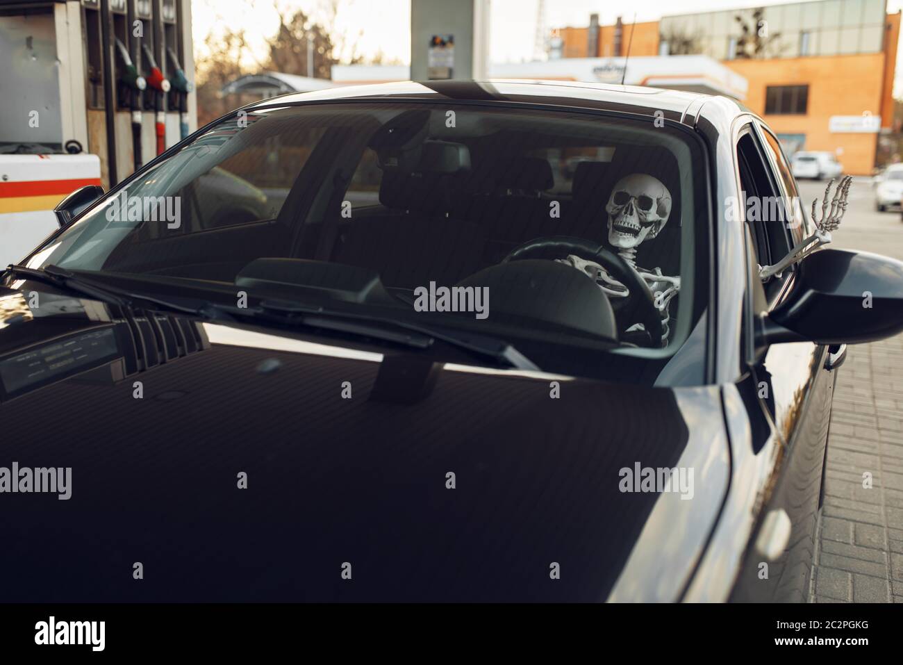 Squelette humain en voiture, ravitaillement en carburant à la station-service, remplissage de carburant. Service de ravitaillement en essence, essence ou diesel, ravitaillement en pétrole Banque D'Images