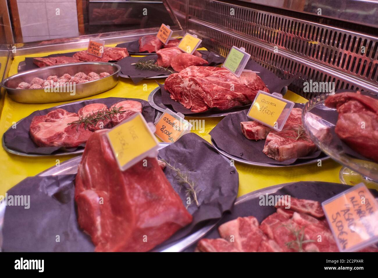 Coupes de viande de veau crues dans un comptoir froid avec étiquettes de prix prêtes à être vendues dans la boutique du boucher. Banque D'Images