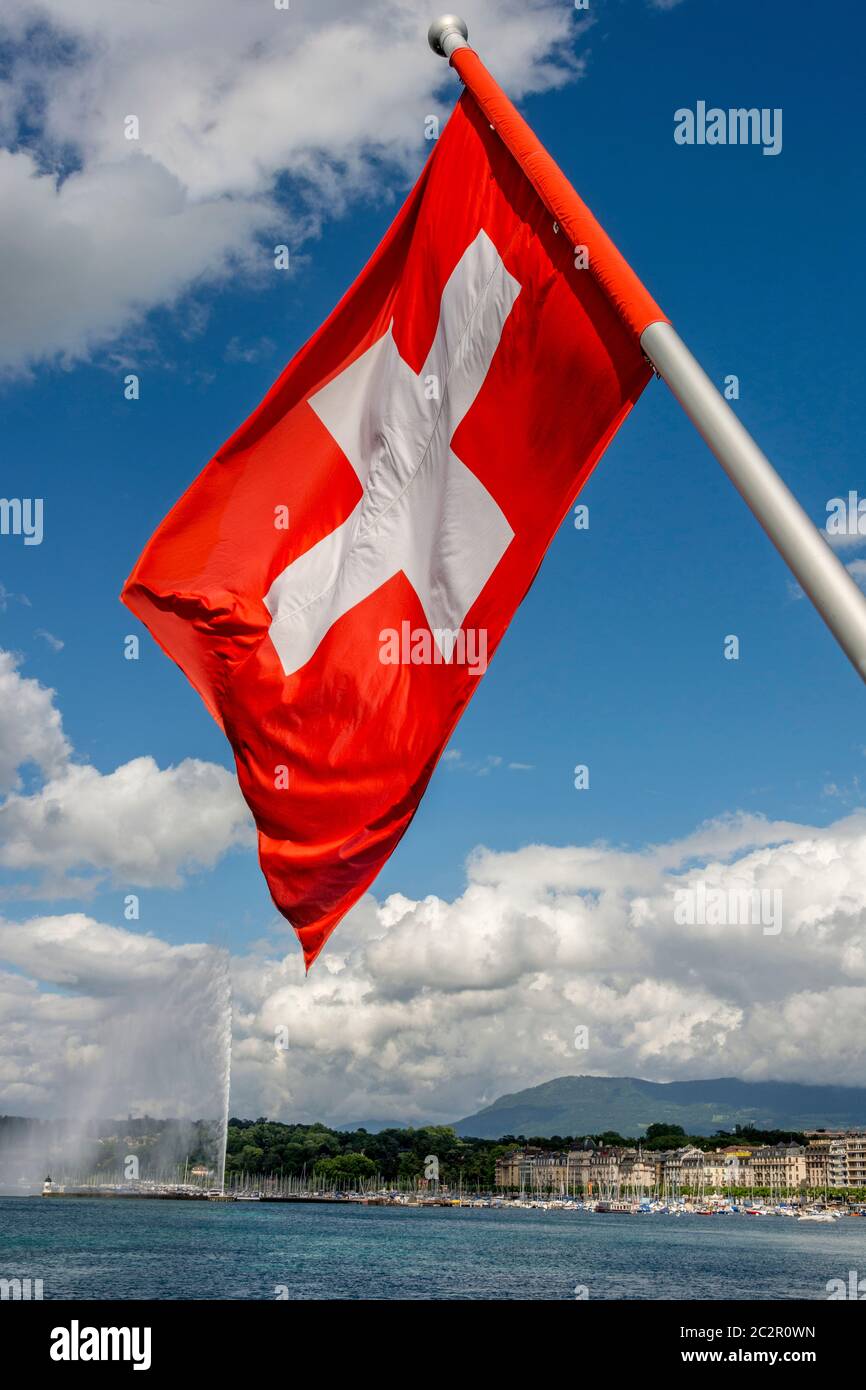 Le drapeau suisse fait des vagues fières près de Jet d'eau sur le lac Léman dans le canton de Genève sous un ciel dégagé. Suisse Banque D'Images