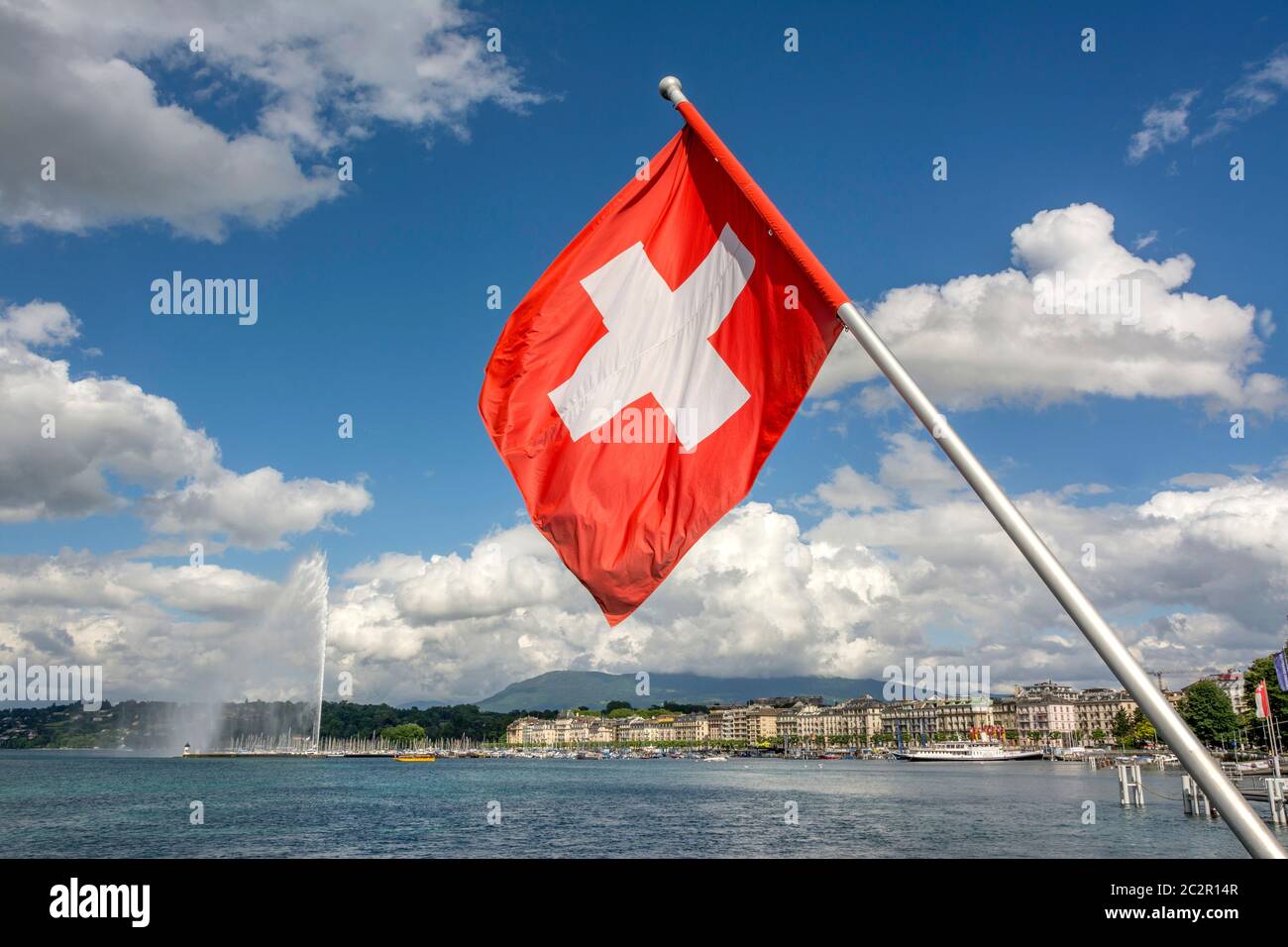 Le drapeau suisse fait des vagues fières près de Jet d'eau sur le lac Léman dans le canton de Genève sous un ciel dégagé. Suisse Banque D'Images