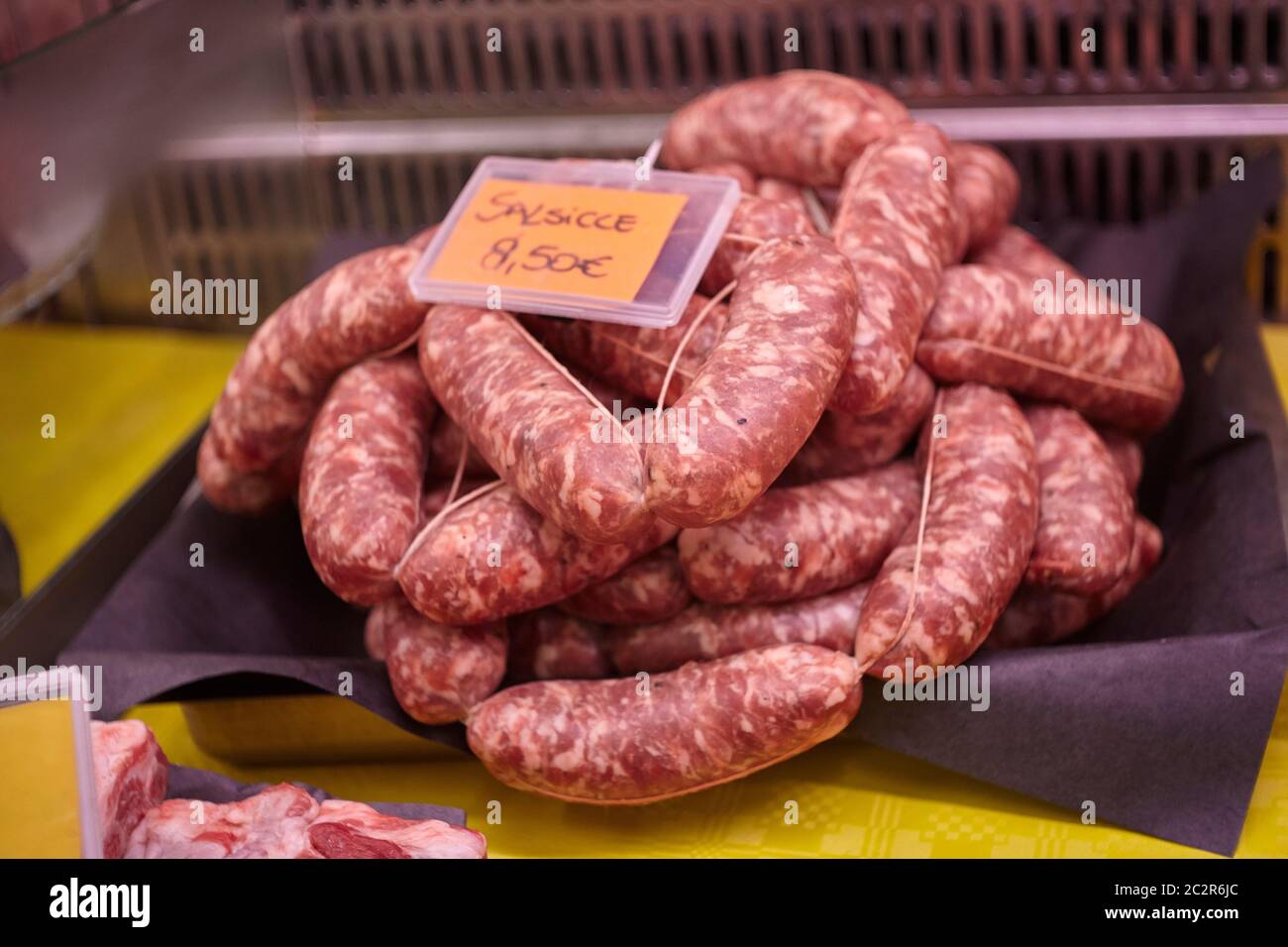 Saucisses de veau crues dans un comptoir avec étiquettes de prix prêtes à être vendues dans la boutique du boucher. Banque D'Images