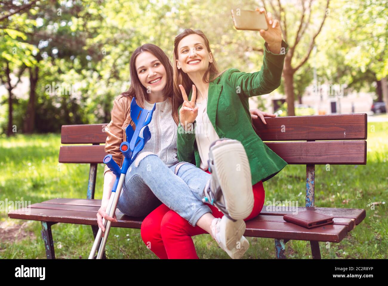 Meilleurs amis avec un ayant une jambe cassée prenant un selfie au téléphone Banque D'Images