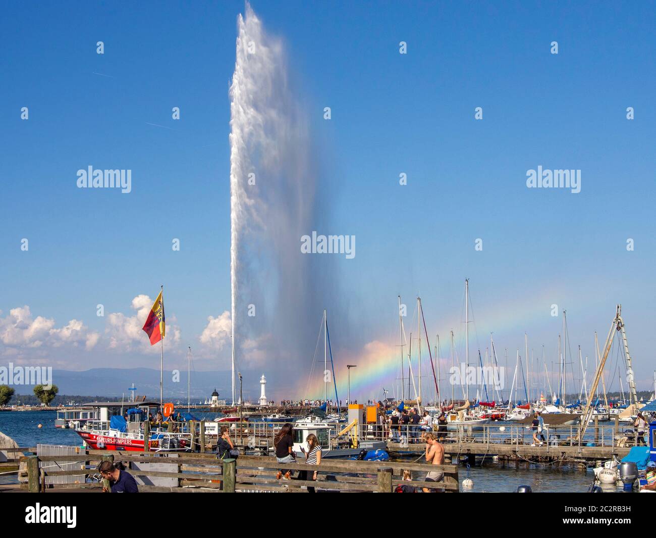 Fontaine jet d'eau au lac Léman avec bateaux et ciel bleu clair dans le canton de Genève, Suisse Banque D'Images
