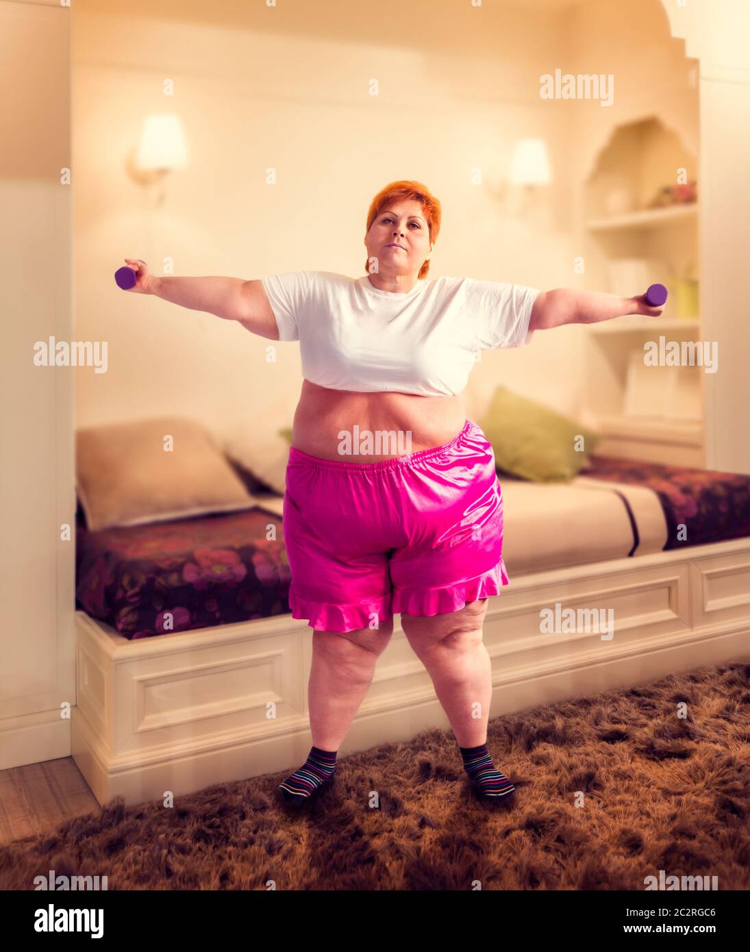 Grosse femme sur la formation avec haltères courtes, lutte contre l'obésité, l'excès de poids. Manger de la restauration rapide Banque D'Images