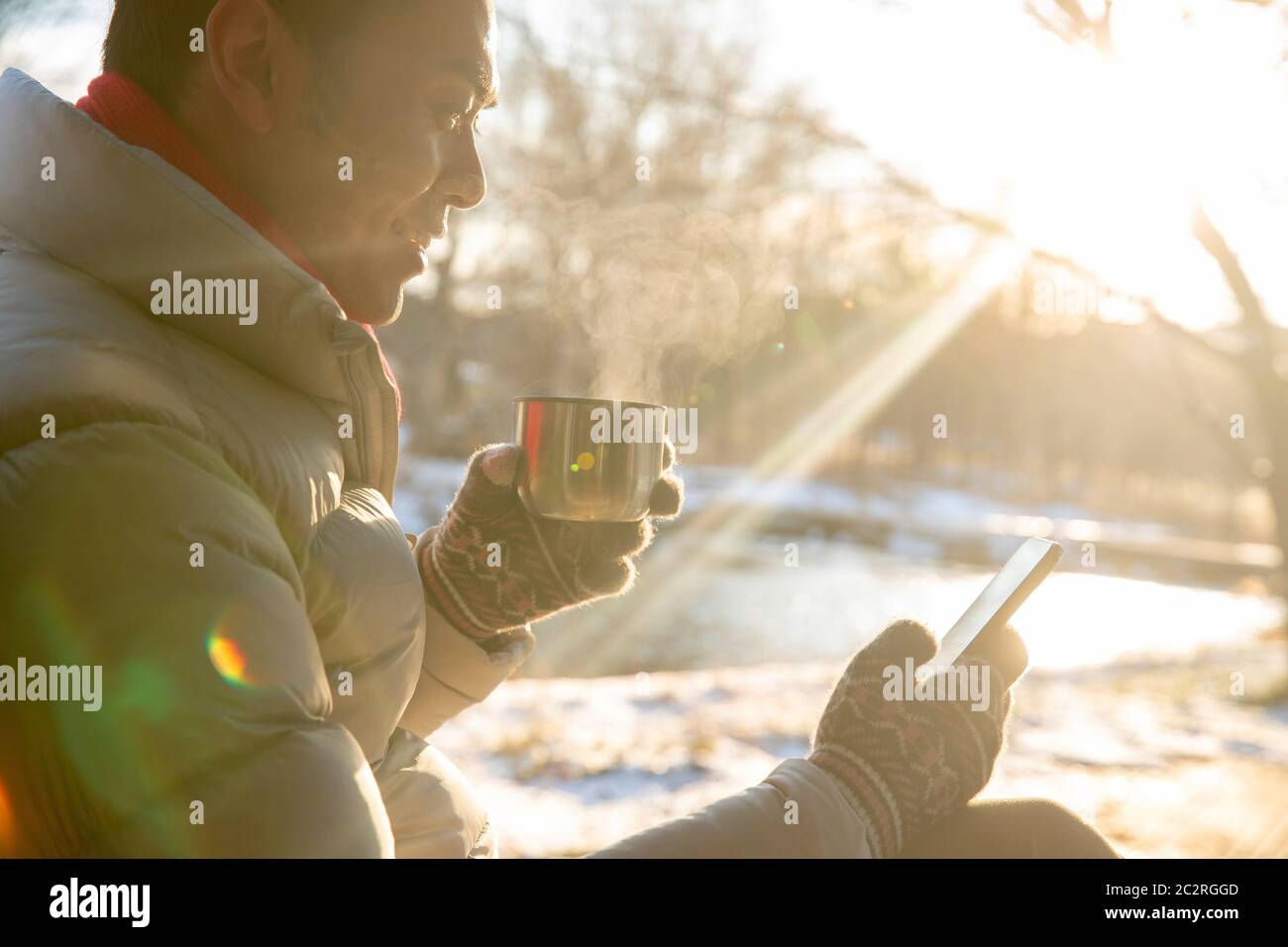 L'homme assis dans la neige pour voir le téléphone portable Banque D'Images