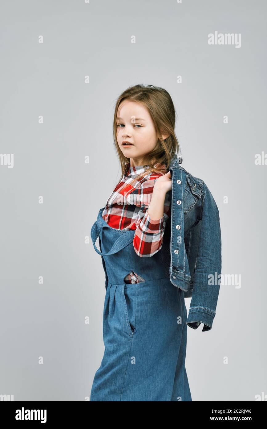 Portrait d'une petite fille tendance dans une chemise à carreaux et une  combinaison en denim. studio Fashion Shooting Photo Stock - Alamy