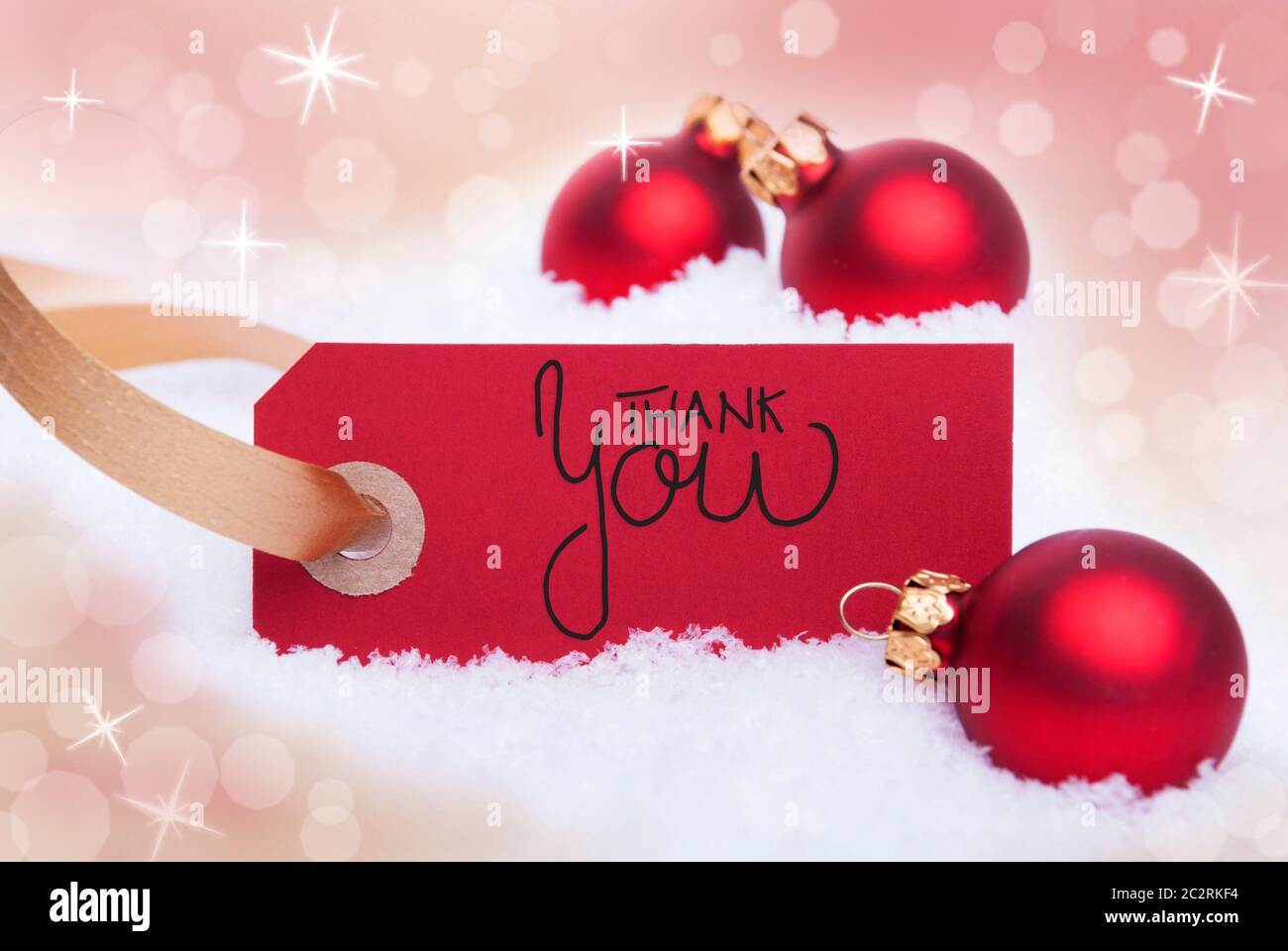 Label Rouge avec calligraphie anglaise Je vous remercie. Boule de noël ornement. Flou d'arrière-plan avec la neige brillant Banque D'Images