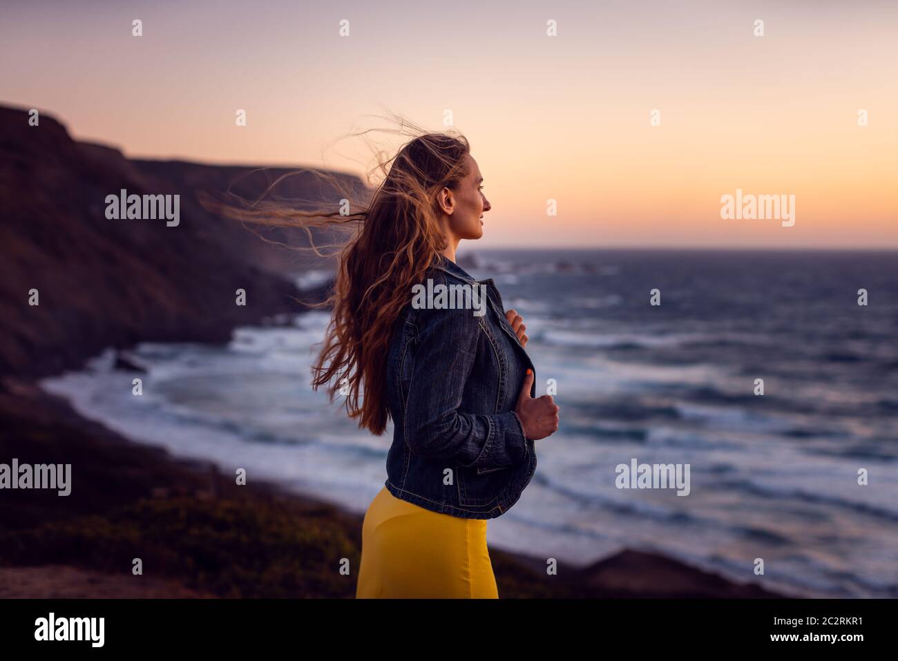 Femme sur une plage de coucher de soleil avec le vent dans ses cheveux étant libre Banque D'Images