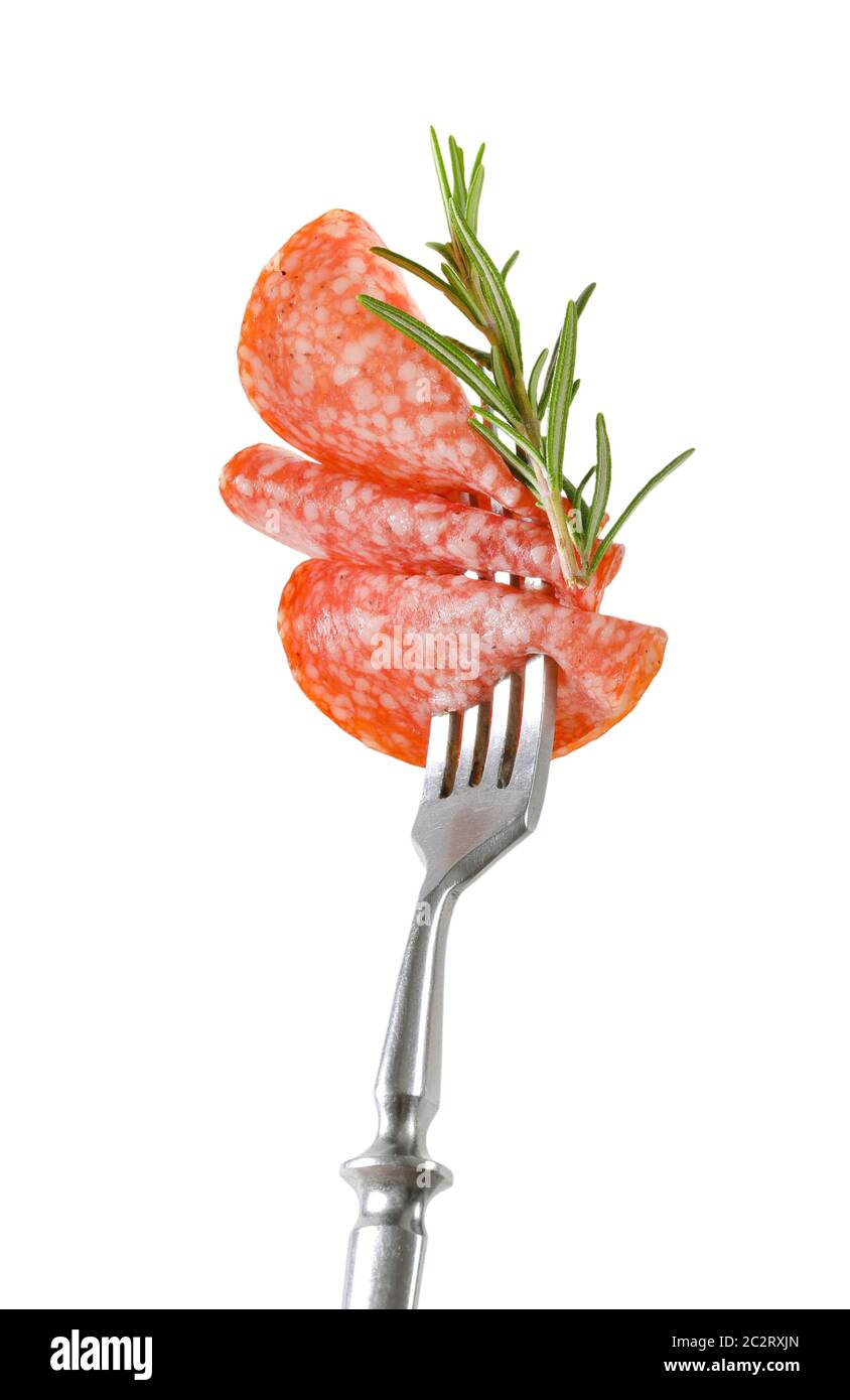 Tranches de salami hongrois et de romarin frais sur fourche isolées sur blanc Banque D'Images