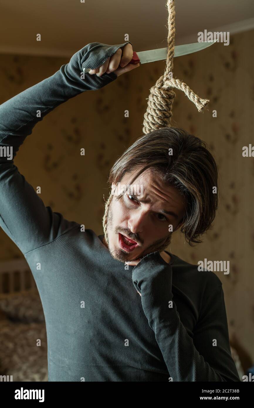 Homme déprimé avec un nœud autour de son cou essayant de couper la corde avec le couteau. Banque D'Images