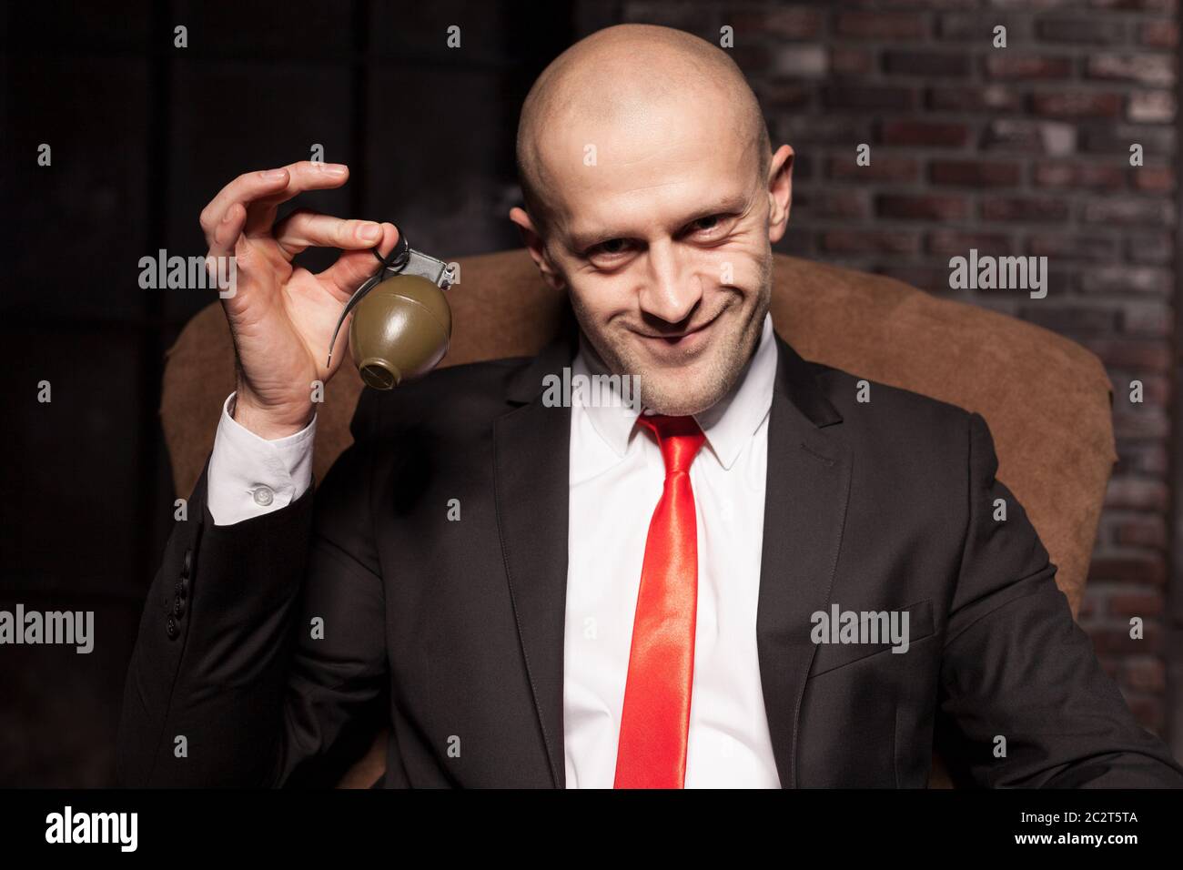 L'agent spécial chauve en costume et cravate rouge tire une grenade borne,  un travail dangereux Photo Stock - Alamy