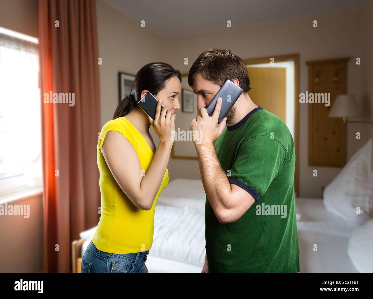 Homme et femme en colère parlant avec un téléphone portable dans la chambre Banque D'Images