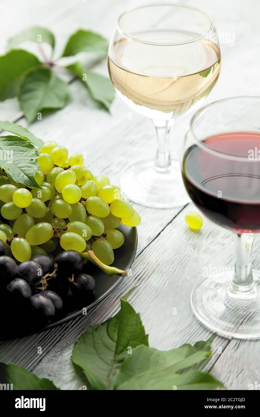 Deux verres avec différentes variétés de vin et une assiette avec différents raisins mûrs. Rouge ou blanc ? Votre choix ! Banque D'Images
