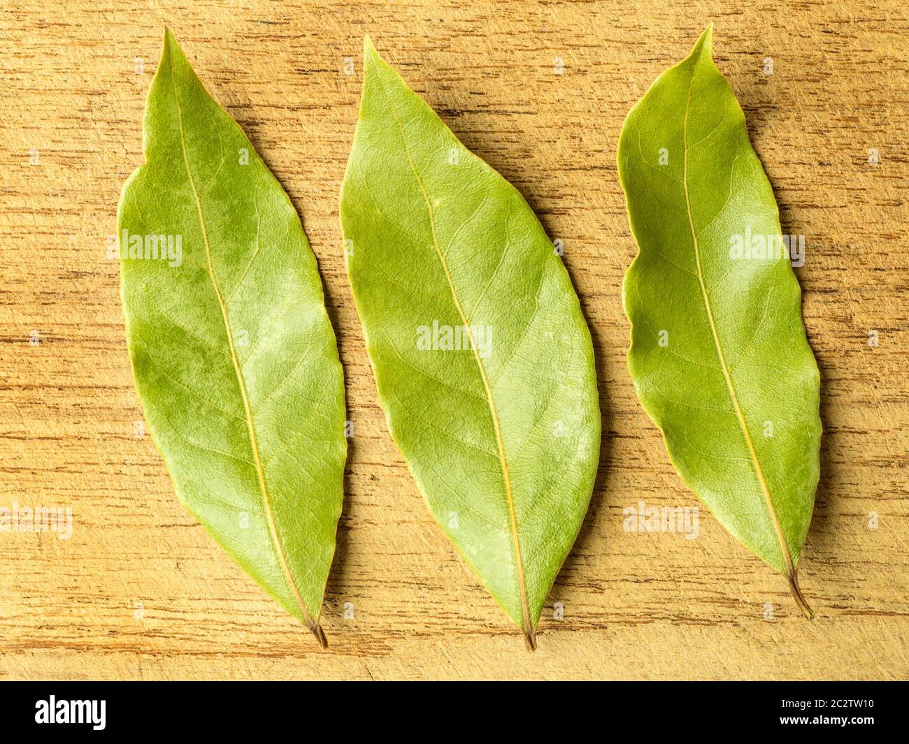 Trois feuilles de Laurier séchées sur une planche à découper en bois Banque D'Images