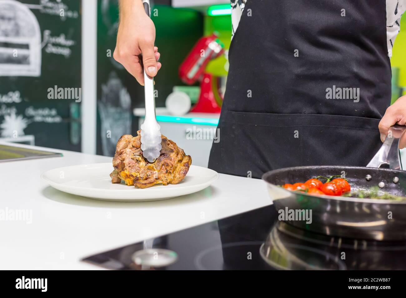 Jeune homme mettant de la viande frite dans l'assiette de la cuisine maison Banque D'Images