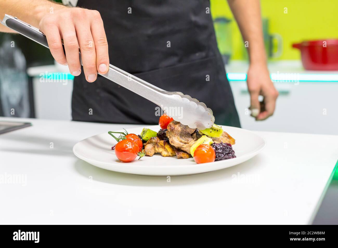 Main de l'homme décorant plat à viande dans la cuisine Banque D'Images
