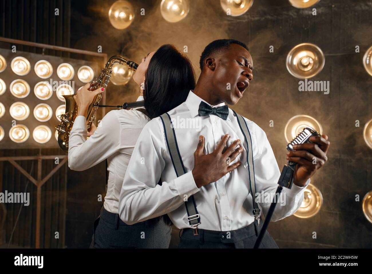 Interprète de jazz masculin et saxophoniste féminine avec saxophone, jouant sur scène avec des spots. Des joueurs de jazz jouent sur la scène Banque D'Images