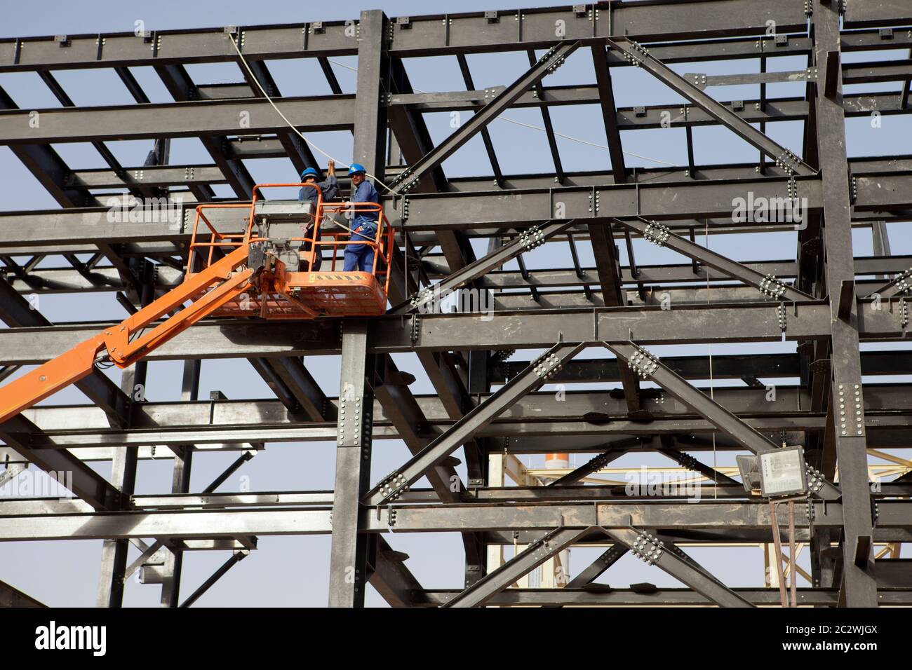 Un ingénieur utilise une plate-forme à élévation élevée lors de la construction de cadres de conduites dans le cadre d'une nouvelle installation pétrolière en cours de construction dans le désert du Sahara. Banque D'Images