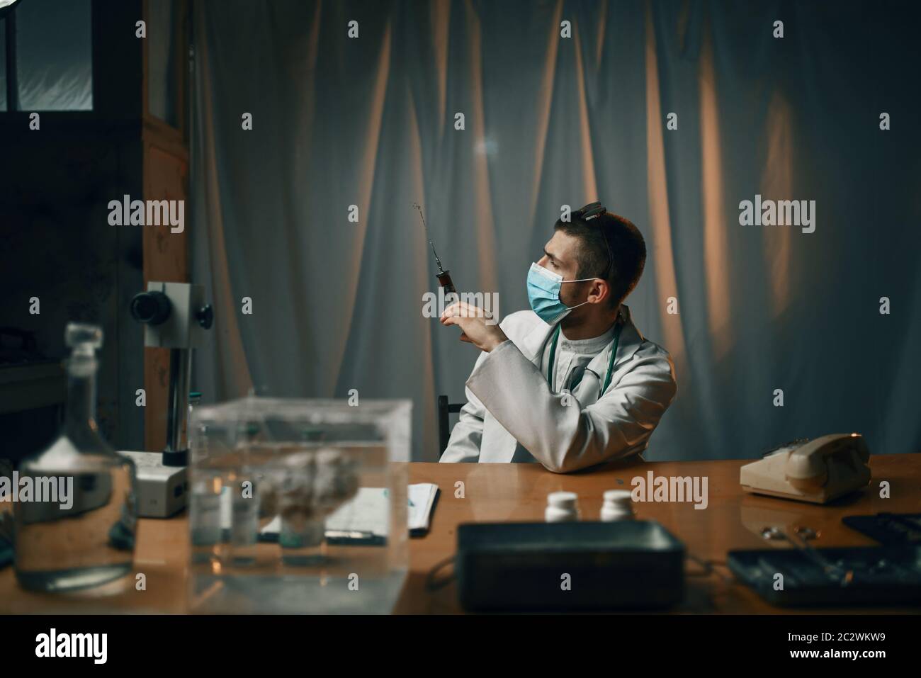 Psychiatre masculin dans un masque tenant une seringue avec un hôpital psychiatrique sédatif. Médecin en clinique pour les malades mentaux Banque D'Images