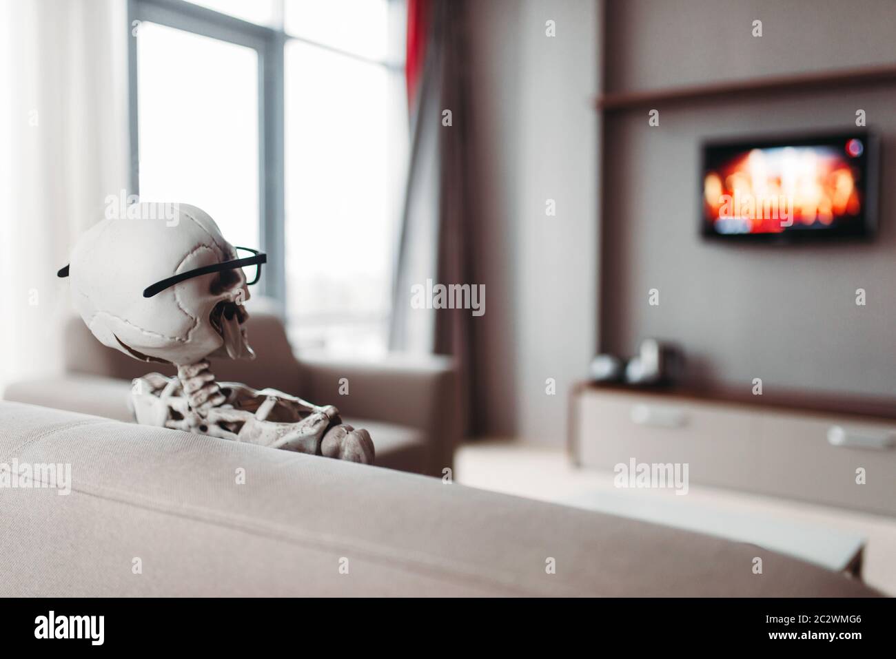 Squelette en lunettes est assis sur le canapé et regarder la télévision,  vue de dos, fenêtre sur l'arrière-plan. Drôle Photo Stock - Alamy