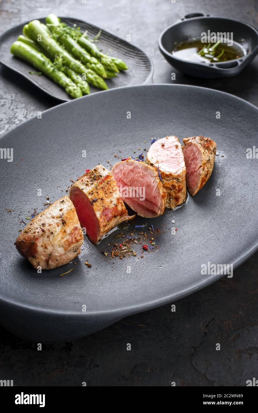 Filet de porc ibérique poêlé coupé en tranches d'asperges vertes blanchies  et sauce au beurre avec épice dans un plat en fonte Photo Stock - Alamy